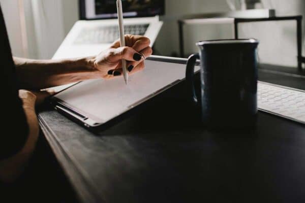 Person Writing On White Paper On Black Table